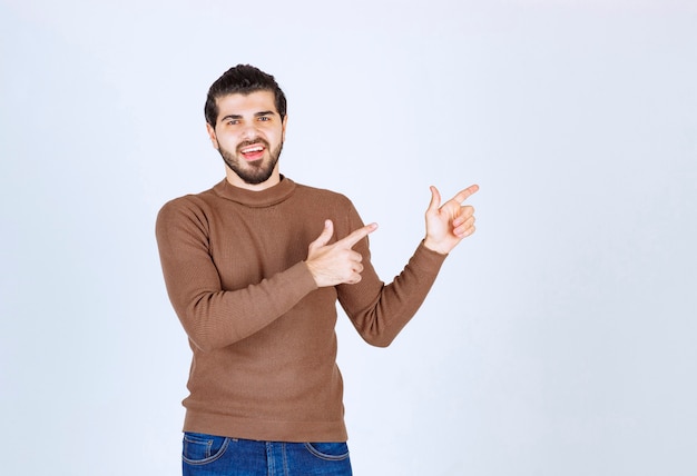 Portret van mannelijk model in bruine sweater die zich over witte muur bevindt. hoge kwaliteit foto