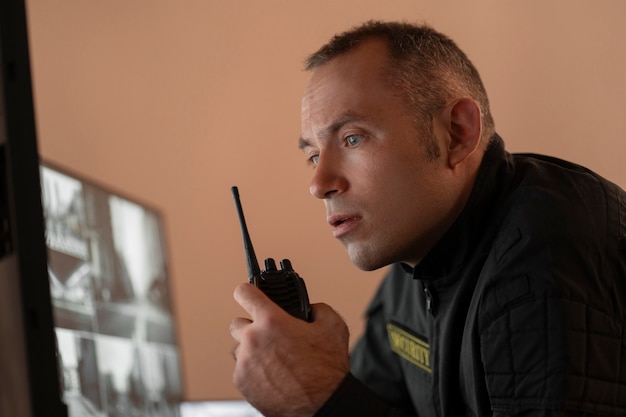 Gratis foto portret van mannelijke bewaker met radiostation en cameraschermen