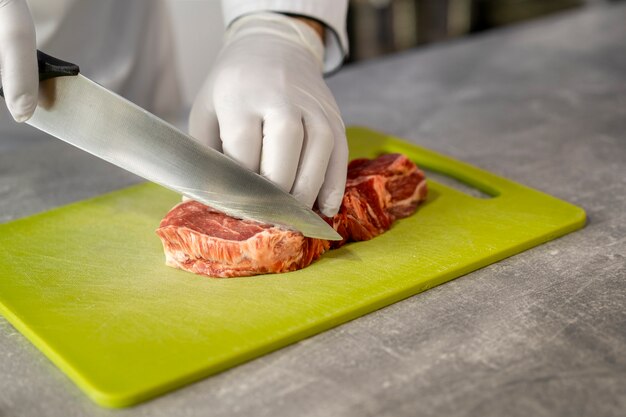 Portret van mannelijke chef-kok in de keuken die vlees voorbereidt