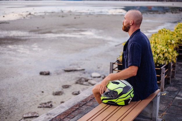 Portret van mannelijke fietser met gele helm zittend op een bankje aan de promenade in Thailand op zonsondergang tijd