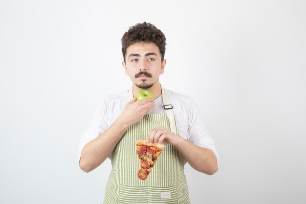 Portret van mannelijke kok met pizza en groene appel op wit