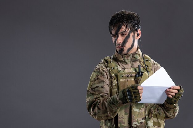 Portret van mannelijke soldaat in camouflage ontvangen brief op donkere muur