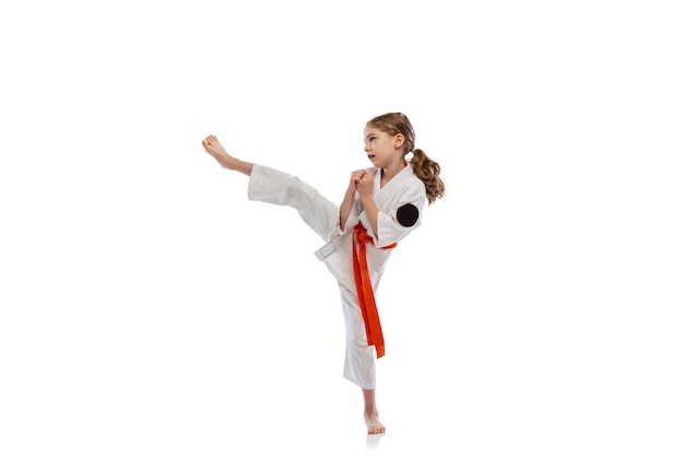 Portret van meisje, kind in kimono opleiding karate geïsoleerd op wit. Gevecht