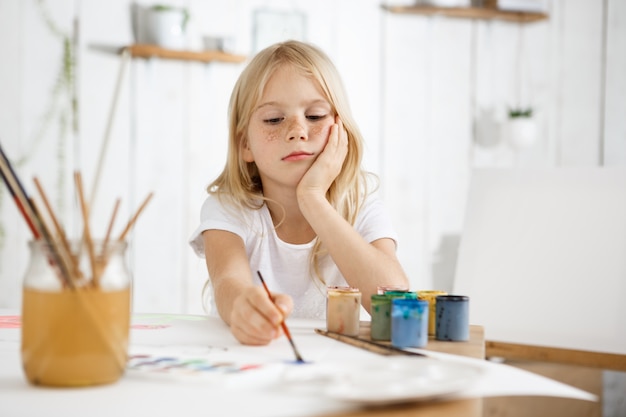 Portret van meisje met blonde haren en sproeten zitten aan de balie en haar elleboog op tafel te zetten