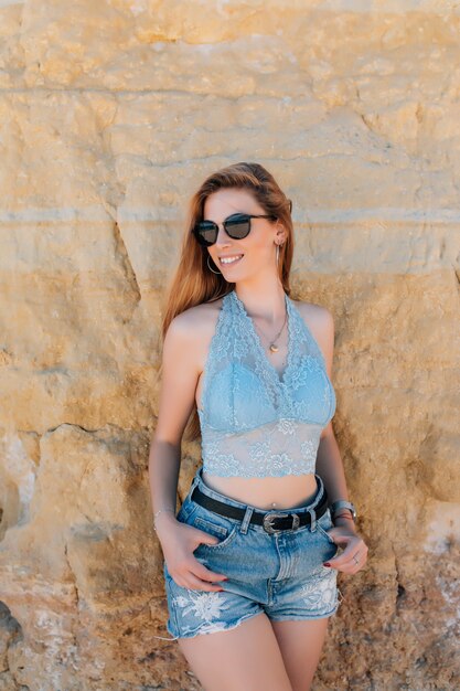 Portret van meisje met lang haar en blauwe ogen die zich voordeed op rotsachtig strand.