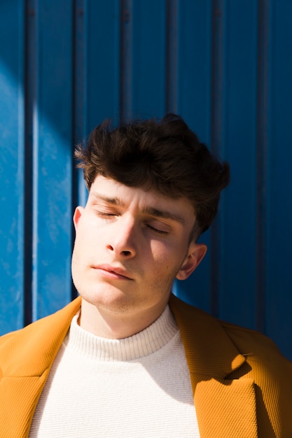 Portret van modieuze jongen tegen blauwe muur