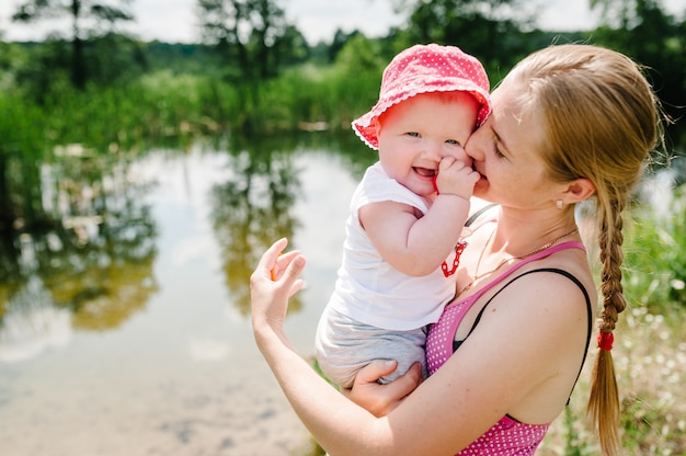 Portret van moeder en meisje in de buurt van lake. gelukkig vrouw spelen met kinderen op de rivier. gelukkig gezin: moeder en dochter buiten.
