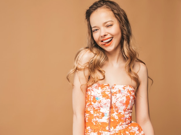 Portret van mooi glimlachend leuk model met roze lippen. Meisje in zomer kleurrijke jurk. Model poseren. Haar tong tonen