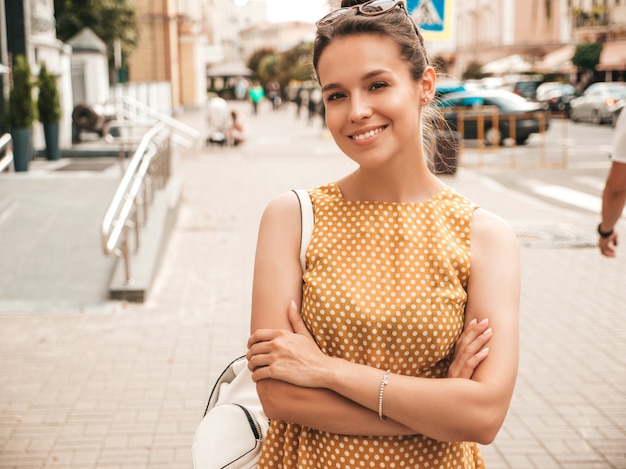 Portret van mooi glimlachend model gekleed in de zomer gele kleding. trendy meisje poseren in de straat. grappige en positieve vrouw die pret heeft