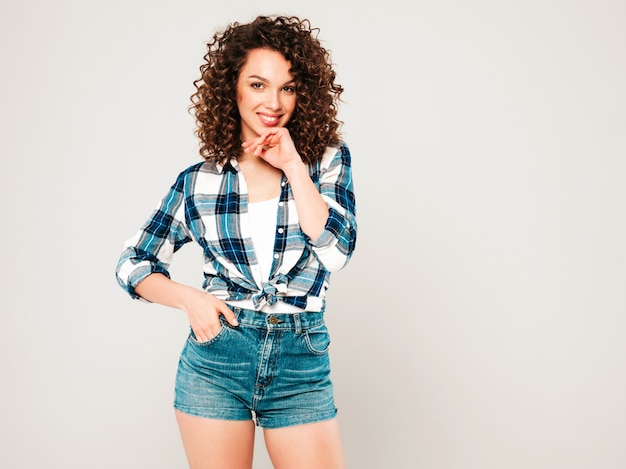 Portret van mooi glimlachend model met afro krullen kapsel gekleed in zomer hipster kleding. sexy zorgeloos meisje poseren in studio op grijze achtergrond. trendy grappige en positieve vrouw