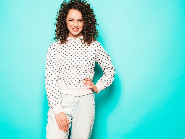 Portret van mooi glimlachend model met afro krullen kapsel gekleed in zomer hipster kleding. Trendy grappige en positieve vrouw knipogen