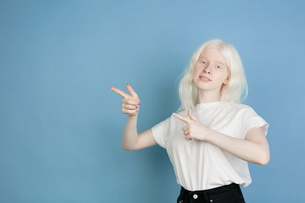 Portret van mooi Kaukasisch albinomeisje dat op blauwe muur wordt geïsoleerd