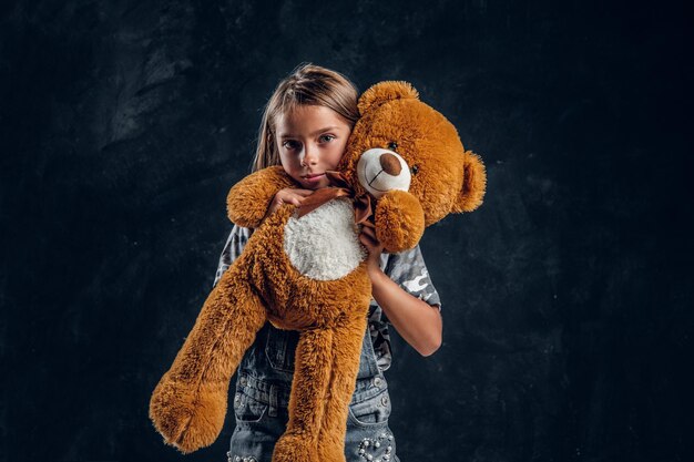 Portret van mooi klein meisje met grote knuffel in fotostudio.