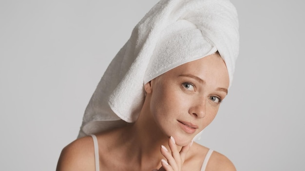Portret van mooi meisje met gladde gezonde huid en handdoek op hoofd geïsoleerd op een witte achtergrond. Schoonheidsconcept