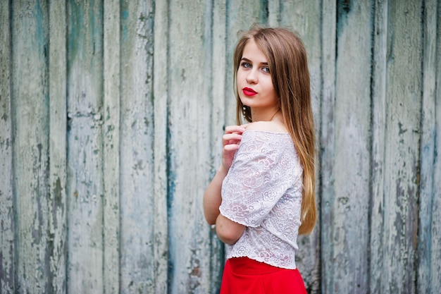 Portret van mooi meisje met rode lippen tegen houten achtergrond slijtage op rode jurk en witte blouse