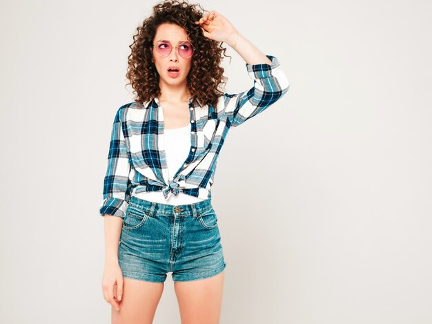 Portret van mooi model met afro krullen kapsel gekleed in zomer hipster kleding. Sexy zorgeloos meisje poseren in studio op grijze achtergrond. Nadenken over haar problemen