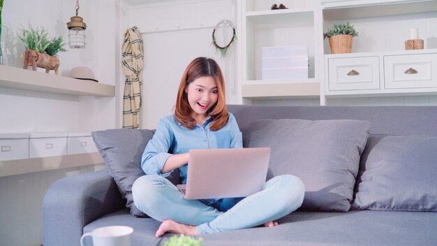 Portret van mooie aantrekkelijke jonge lachende Aziatische vrouw met behulp van computer of laptop