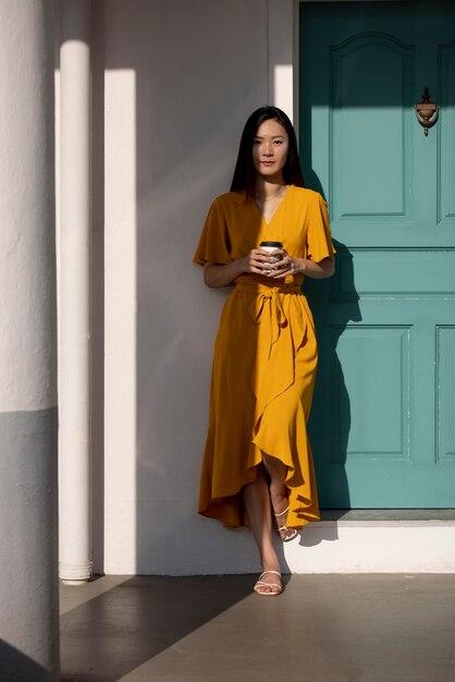 Portret van mooie aziatische vrouw die buiten in de stad poseert terwijl ze koffie drinkt