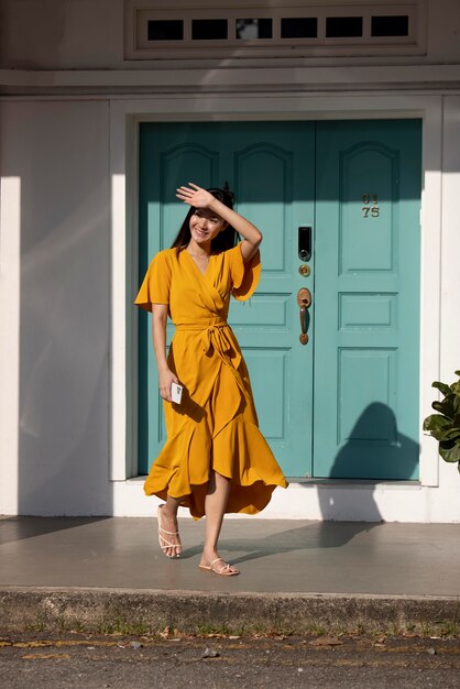 Portret van mooie Aziatische vrouw in gele jurk poseren buiten in de stad