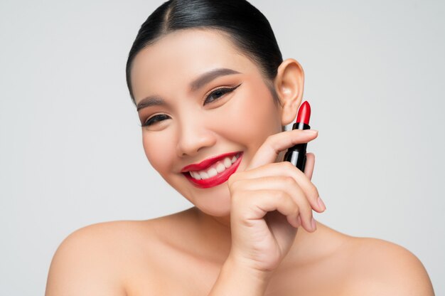 Portret van mooie Aziatische vrouw met lippenstift in de hand
