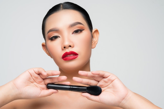 Portret van mooie Aziatische vrouw met make-up blusher borstel