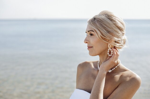 Portret van mooie blonde blanke vrouw op de zonnige dag in de buurt van de zee