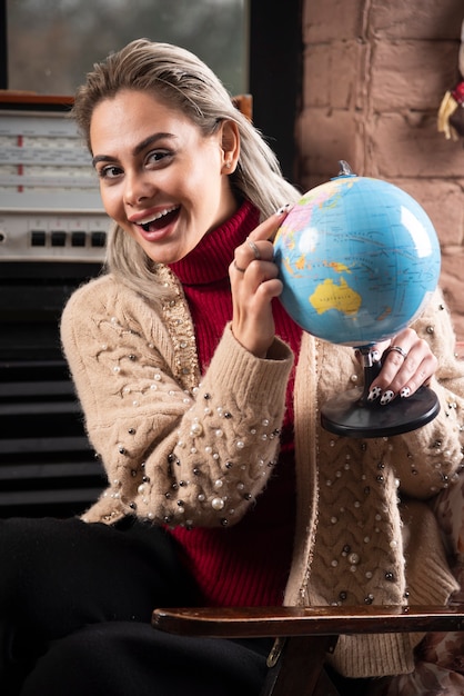 Portret van mooie dame wijzend op een wereldbol