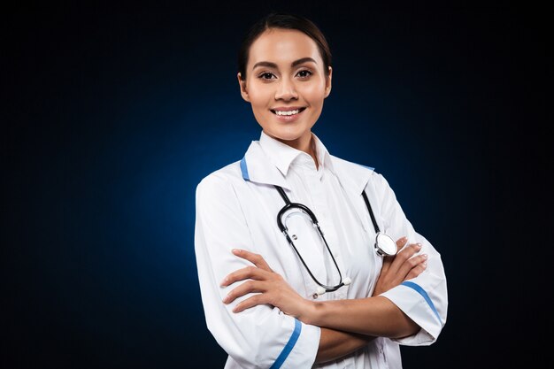Portret van mooie donkerbruine verpleegster die over zwarte wordt geïsoleerd