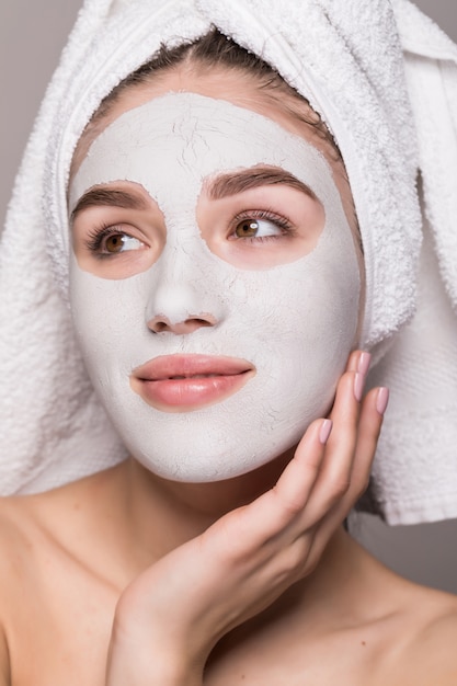 Portret van mooie gelukkig vrouw na douche met een handdoek op haar hoofd met crème masker op gezicht