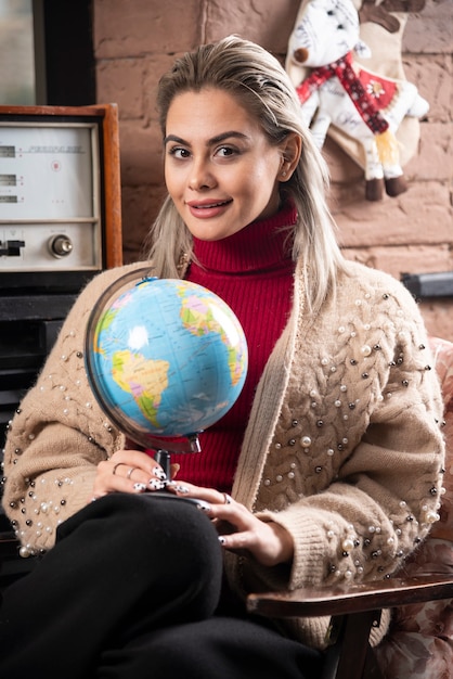 Gratis foto portret van mooie gelukkige dame die een wereldbol houdt