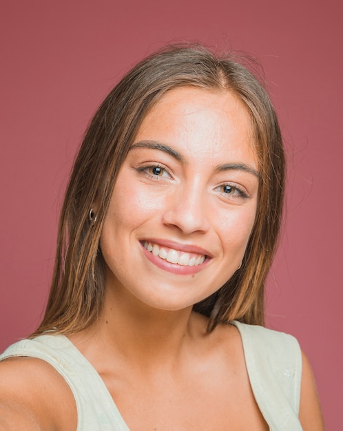 Portret van mooie glimlachende jonge vrouw tegen gekleurde achtergrond