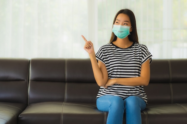 Portret van mooie jonge aziatische vrouw met masker op de sofa