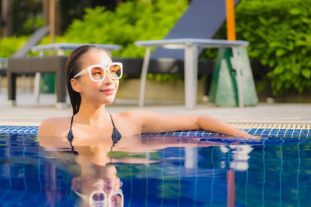 Portret van mooie jonge Aziatische vrouw ontspannen rond buitenzwembad in hotel resort