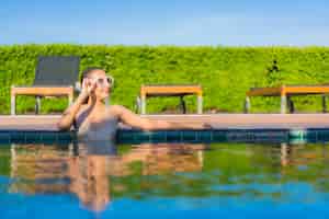Gratis foto portret van mooie jonge aziatische vrouw ontspannen rond buitenzwembad in hotel resort