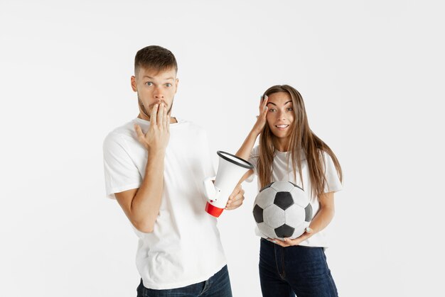 Portret van mooie jonge paar voetbal of voetbalfans op witte muur. Gelaatsuitdrukking, menselijke emoties, reclame, sportconcept. Vrouw en man springen, schreeuwen, plezier maken.