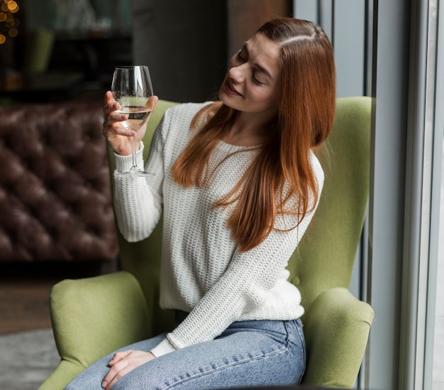 Portret van mooie jonge vrouw die glas wijn bekijkt