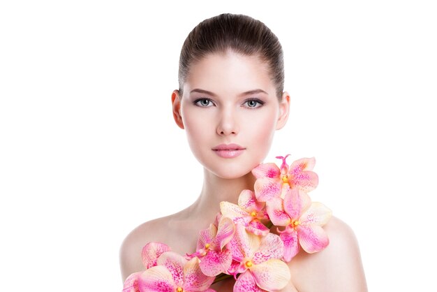 Portret van mooie jonge vrouw met een gezonde huid en roze bloemen op lichaam - dat op wit wordt geïsoleerd