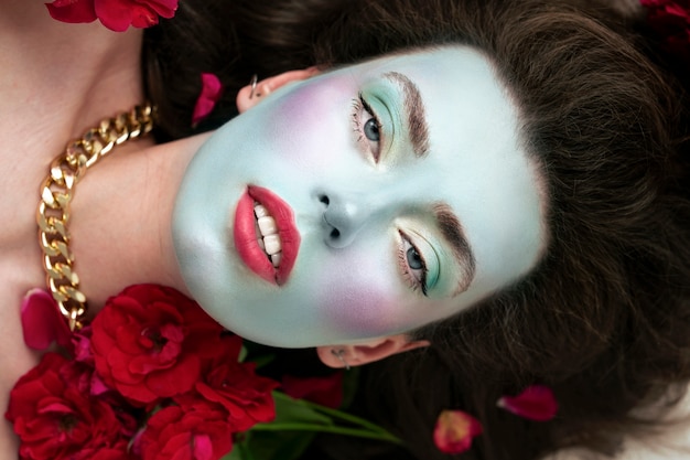 Portret van mooie jonge vrouw met gezichtsverf en bloemen