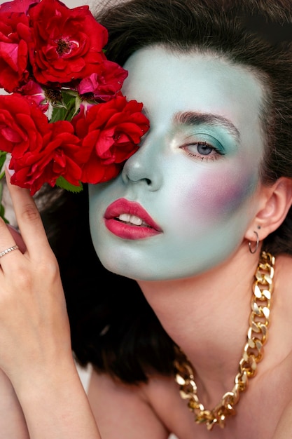 Gratis foto portret van mooie jonge vrouw met gezichtsverf en bloemen