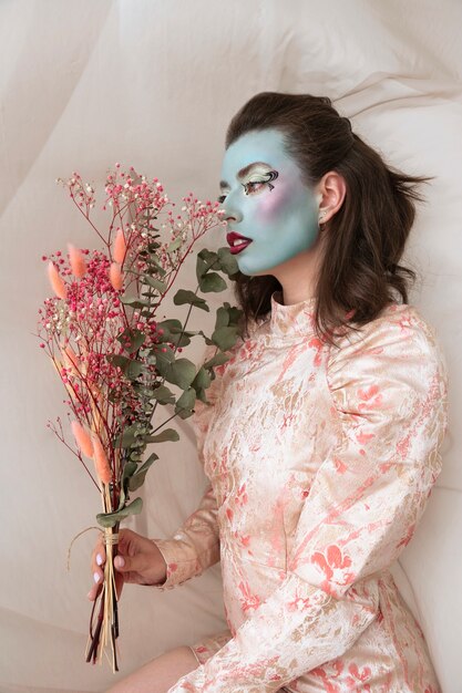Portret van mooie jonge vrouw met gezichtsverf en bloemen