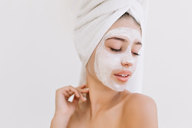 Portret van mooie jonge vrouw met handdoeken na bad nemen cosmetisch masker op haar gezicht.