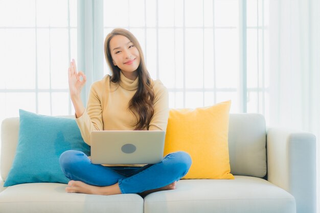 Portret van mooie jonge vrouw met laptop op de bank in de woonkamer