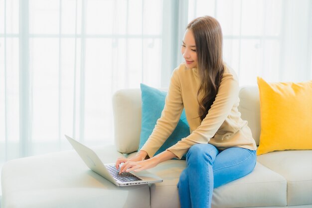 Portret van mooie jonge vrouw met laptop op de bank in de woonkamer