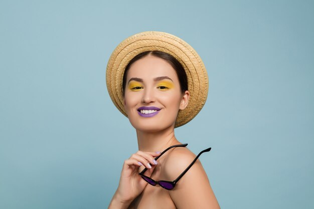 Portret van mooie jonge vrouw met lichte die samenstelling op blauwe muur wordt geïsoleerd