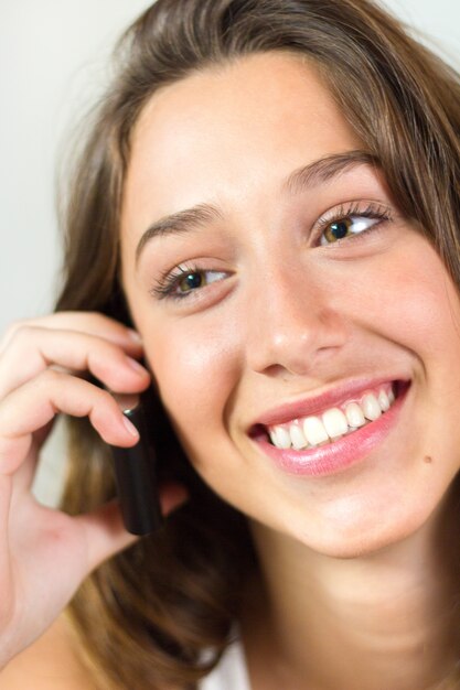 Portret van mooie jonge vrouw thuis met mobiel.