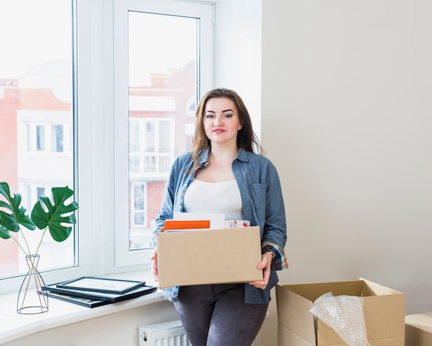 Portret van mooie jonge vrouw uitpakkende kartonnen dozen bij haar nieuwe huis