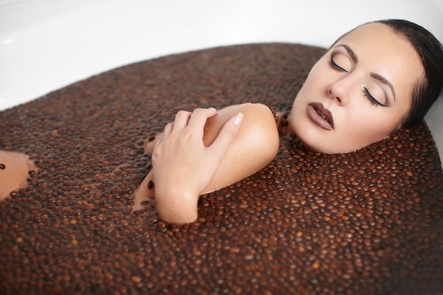 Portret van mooie mode vrouw in jacuzzi met koffie. lichaamsverzorging. lichte make-up