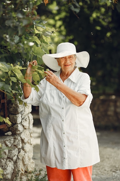 Portret van mooie oude vrouw in het park. Oma in een witte hoed.