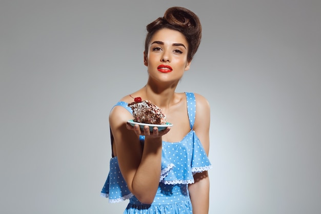 Portret van mooie pin-up vrouw met cake in handen