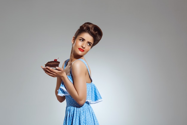 Portret van mooie pin-up vrouw met cake in handen